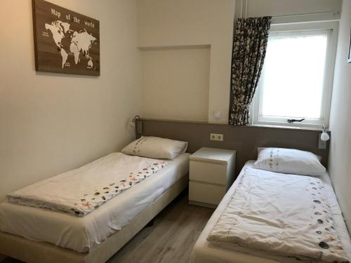 two beds in a small room with a window at Hendrikhof - vakantiewoning Noordkerkepad 5 in Westkapelle