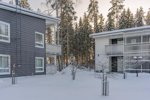 a house in the snow with trees in the background at Saimaa Life Apartments in Imatra