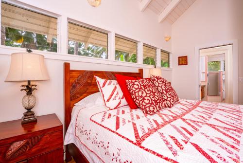 1 dormitorio con cama, lámpara y ventanas en Moloa'a Bay Cottage, en Anahola