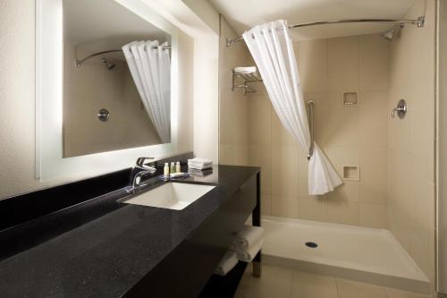 a bathroom with a sink and a tub and a mirror at Wingate Slidell New Orleans in Slidell