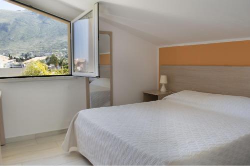 a bedroom with a white bed and a large window at Borgo Aranci - Villa Tulipano in Castellammare del Golfo