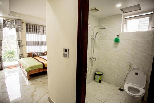 a bathroom with a shower and a toilet and a bedroom at Ngoc Trai 02 FLC Sam Son in Sầm Sơn