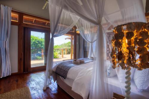 a bedroom with a white bed with a large window at Aloha 6 in Ponta Mamoli
