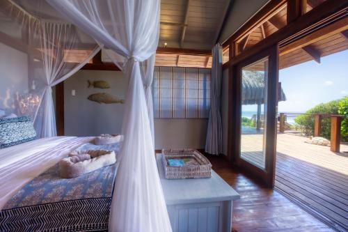 a bedroom with a canopy bed with a view of the ocean at Aloha 6 in Ponta Mamoli