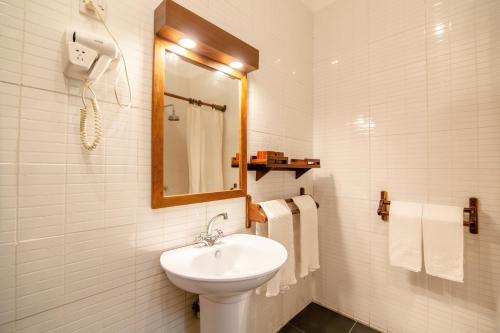a bathroom with a sink and a mirror and towels at Mediterraneo Boutique Hotel in Dar es Salaam