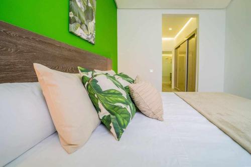 ein Bett mit drei Kissen und einer grünen Wand in der Unterkunft Ocean Garden Suite 11 con jardín privado in Adeje