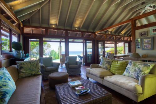 a living room with couches and chairs and the ocean at Aloha 6 in Ponta Mamoli