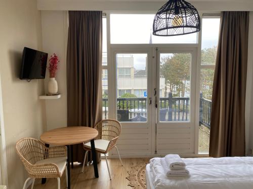 Cette chambre comprend un lit, une table et une fenêtre. dans l'établissement Hotel Doppenberg, à Zandvoort