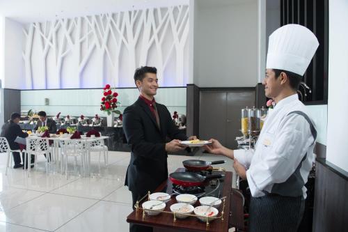 a man and a woman holding a plate of food at Grand Alora Hotel in Alor Setar