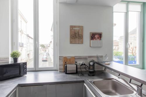 a kitchen with a sink and a microwave at Le RI-BELLOT de 1 à 4 pers - Lit King Size in Cognac