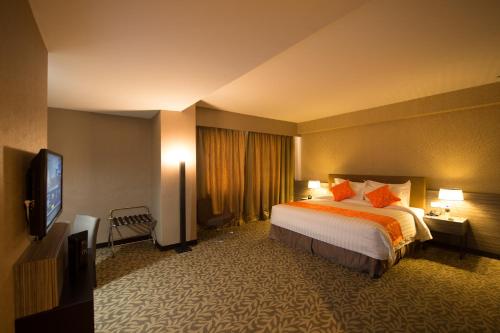 a hotel room with a bed and a flat screen tv at Grand Alora Hotel in Alor Setar