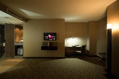 a hotel room with a desk and a tv on the wall at Grand Alora Hotel in Alor Setar