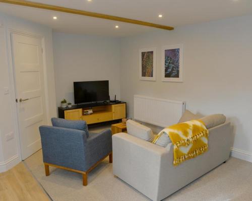a living room with two chairs and a television at Nest House Super cosy one bedroom detached lodge center Huntingdon in Huntingdon