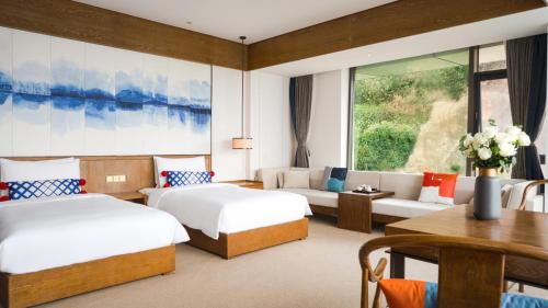 大理市にあるHotel Indigo Dali Erhai, an IHG Hotelのベッド2台とソファが備わるホテルルームです。