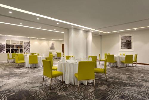 a conference room with tables and yellow chairs at Wyndham Garden Muscat Al Khuwair in Muscat