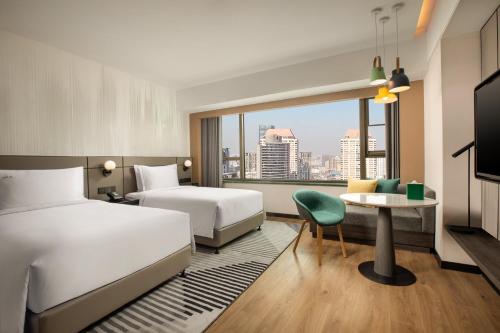 a hotel room with two beds and a table at Holiday Inn Shanghai Nanjing Road by IHG in Shanghai