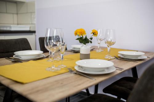 a wooden table with plates and glasses and flowers on it at Apartments Dora Sveti Martin na Muri in Sveti Martin na Muri