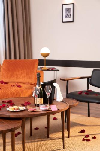 a living room with a couch and a table with wine glasses at Hôtel du Port in Nogent-sur-Marne