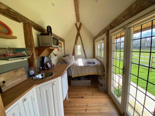 uma cozinha com um lavatório e uma cama num quarto em The Hat's Hut em Mixbury