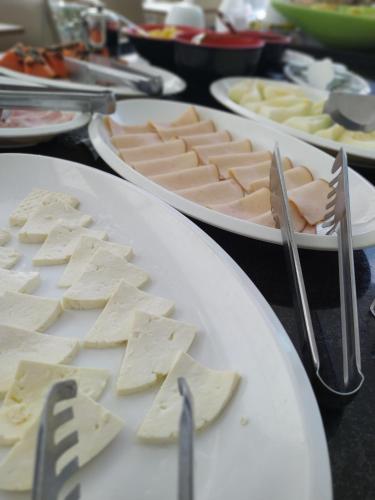 a table with plates of cheese and tongs and forks at ibis Presidente Prudente Manoel Goulart in Presidente Prudente