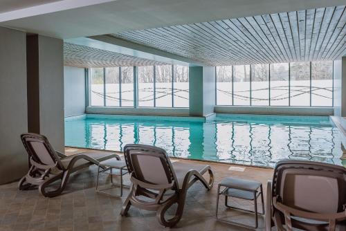 a swimming pool with chairs and a large window at Ensana Ursina in Sovata