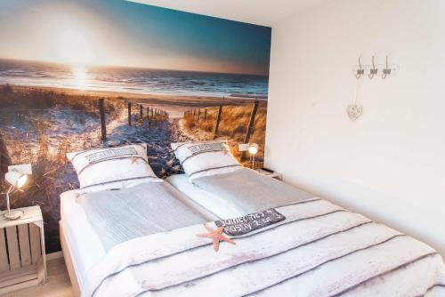 two beds in a room with a painting of the beach at Bungalow Sunny, lekker uitwaaien op het strand! in Callantsoog