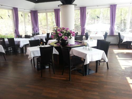 a dining room with white tables and chairs and flowers at Hotel Forsthaus in Berlin