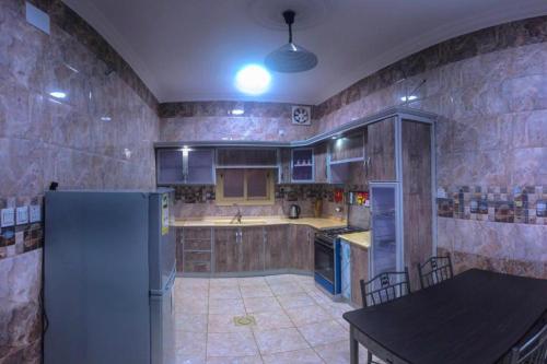 a kitchen with a refrigerator and a table in it at Al Tal Serviced Apartments in Baljurashi