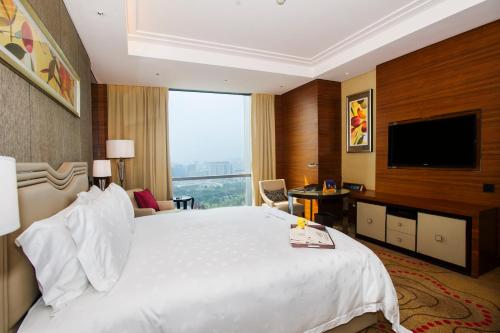a hotel room with a large bed and a flat screen tv at Dongguan Kande International Hotel in Dongguan