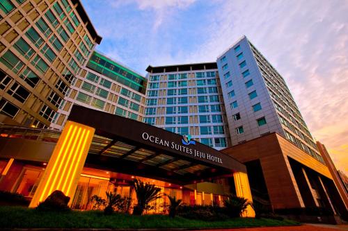 an office building with a sign in front of it at Ocean Suites Jeju Hotel in Jeju