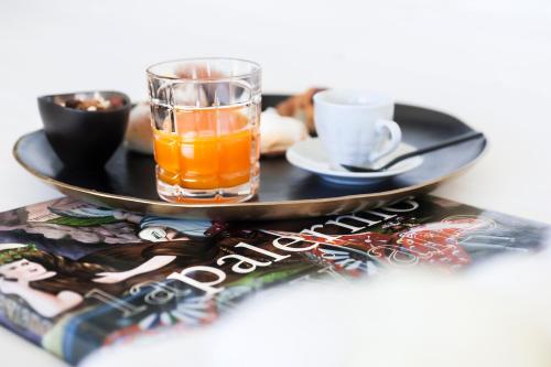 a black plate with a glass of orange juice on a table at Miceli Exclusive Suite in Palermo
