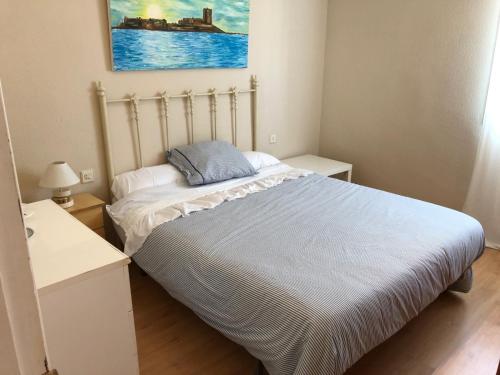 a bedroom with a bed and a painting on the wall at Apartamento Playa La Barrosa in Chiclana de la Frontera