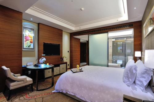 a bedroom with a bed and a desk and a tv at Dongguan Kande International Hotel in Dongguan