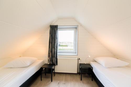 two beds in a room with a window at Onder de Pannen in Hollum