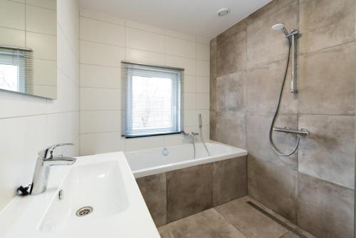 een badkamer met een bad, een wastafel en een douche bij Onder de Pannen in Hollum