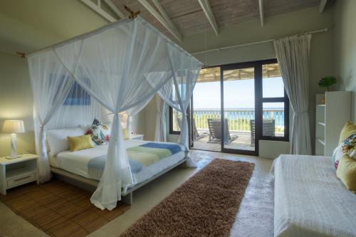 a bedroom with a canopy bed and a balcony at Kangela 9 in Ponta Malongane