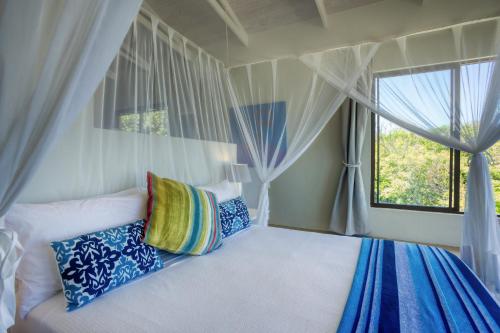 a bedroom with a bed with pillows and a window at Kangela 9 in Ponta Malongane