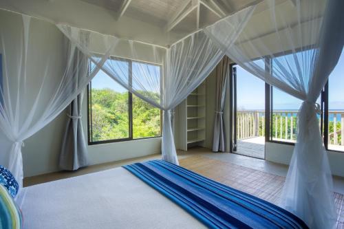 a bedroom with a canopy bed with a view of the ocean at Kangela 9 in Ponta Malongane