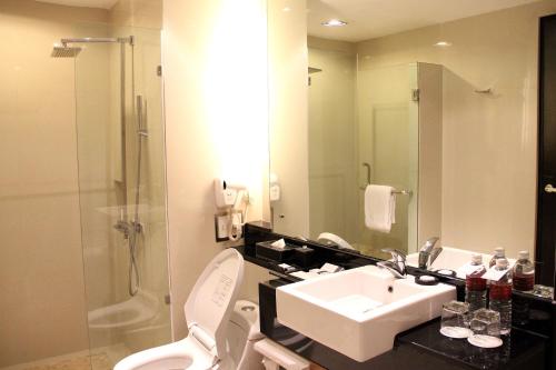 a bathroom with a sink and a toilet and a shower at Grand City Hall Hotel & Serviced Residences in Medan