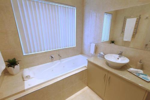 a bathroom with a tub and a sink and a mirror at Casavino Luxury Villa in McLaren Vale