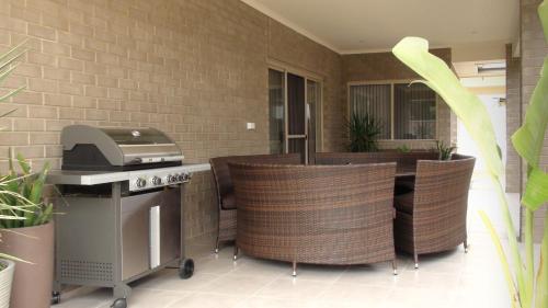 an outdoor kitchen with a grill and wicker chairs at Casavino Luxury Villa in McLaren Vale