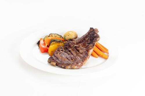 a plate of steak and vegetables on a white plate at Petit Palais Platres Boutique Hotel in Platres