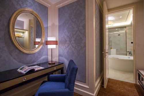 a bathroom with a blue chair and a desk and a mirror at Dongguan Kande International Hotel in Dongguan