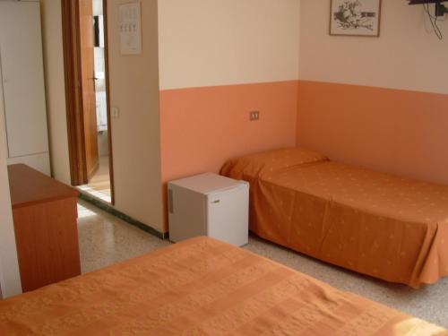 two beds in a room with orange walls at Hotel Saturno in Chianciano Terme