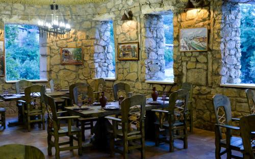 een eetkamer met tafels en stoelen en een stenen muur bij hotel Magnolia in the city centre in Koetaisi