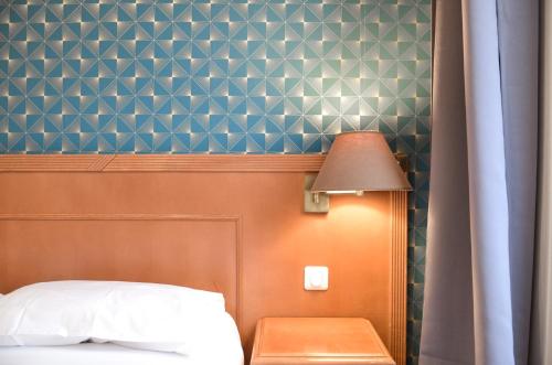 a bedroom with a bed and a lamp and a table at Hôtel De La Perdrix Rouge in Paris