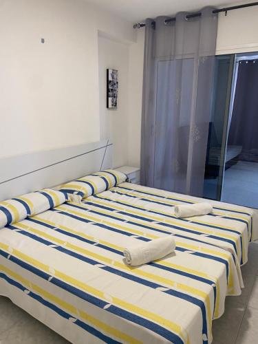 ベニドルムにあるTropic Marの黄色と青のストライプを用いた客室内のベッド2台