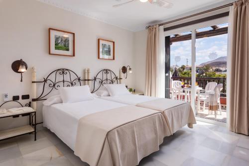 a white bedroom with two beds and a balcony at Parque Santiago V Official in Playa de las Americas