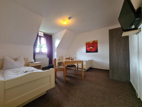 a bedroom with a bed and a table and a television at Hotel Ceteno in Wunstorf