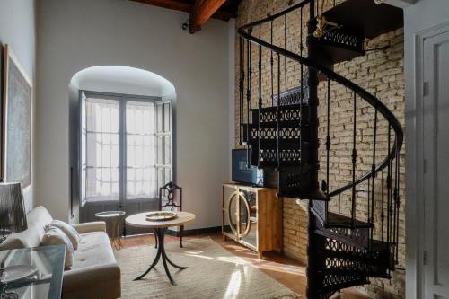 sala de estar con pared de ladrillo y escalera de caracol en Hospederia Santa Clara, en Utrera